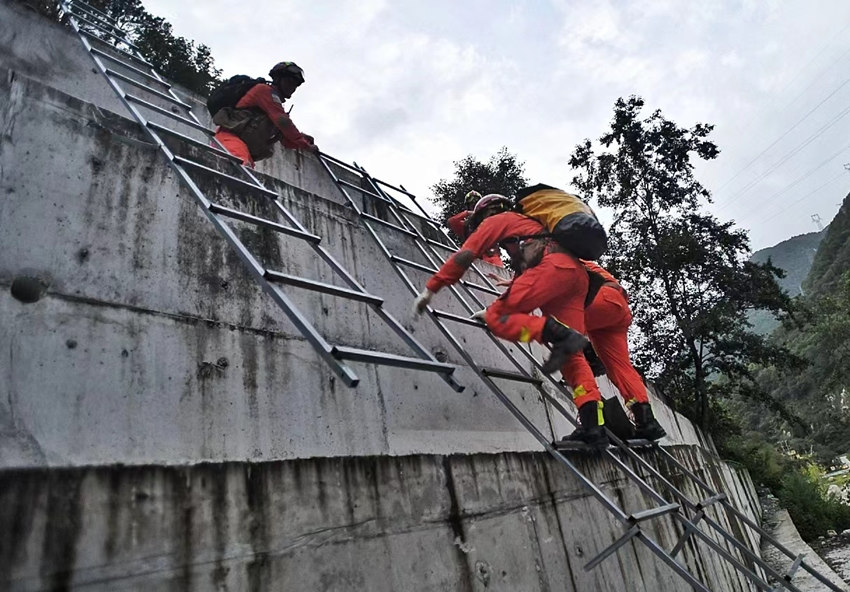 9月5日19時左右，消防員們呈一路縱隊，沿著搭建的鋼梯與繩索，手腳并用翻越山頭、大壩向震中挺進。華小峰攝