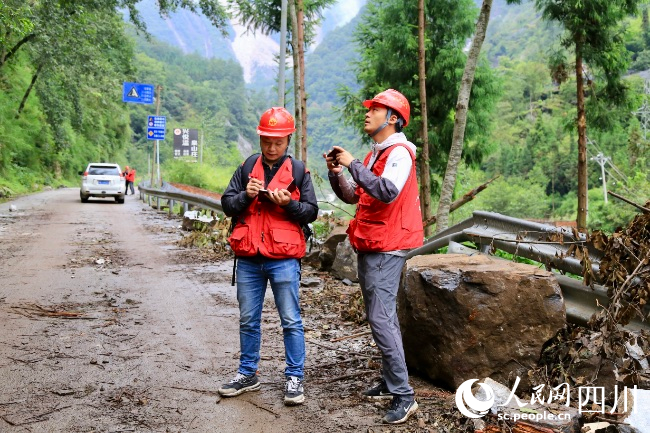 萬利宴（左）和同事在現(xiàn)場進(jìn)行地質(zhì)災(zāi)害隱患排查。人民網(wǎng) 朱虹攝