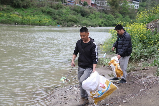 董正建父子在河道邊清理垃圾。馬發海攝