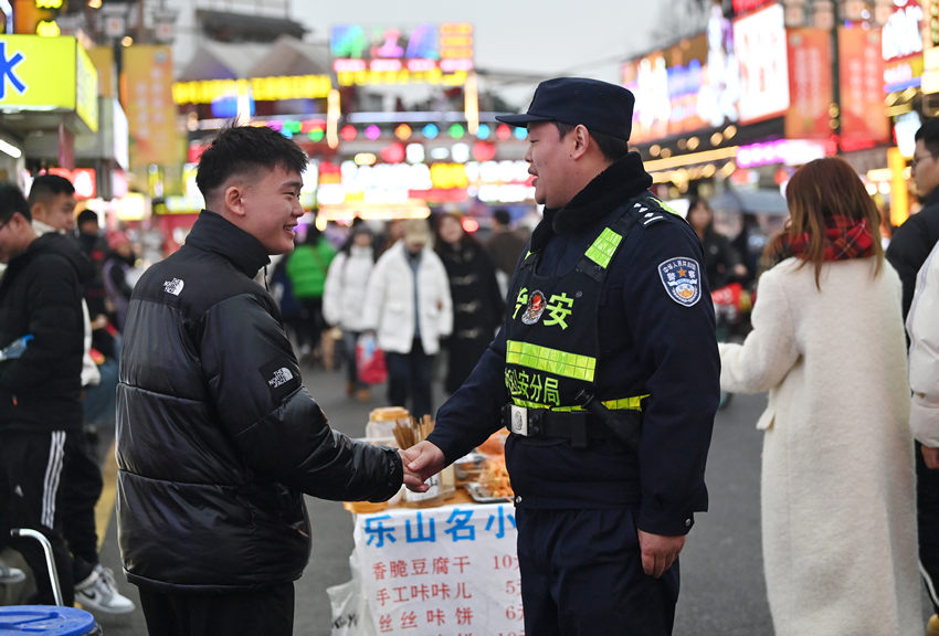 被幫助的游客和樂山市公安局市中區分局張公橋派出所副所長白科翔握手，表示感謝。樂山公安供圖