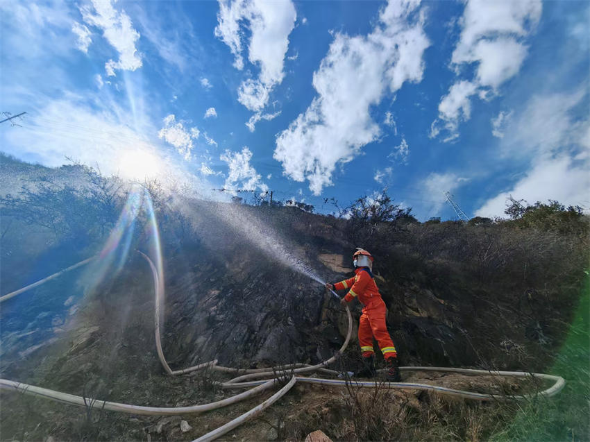 眉山市消防救援支隊救援人員利用40水帶出槍，對雅江縣降央寺周邊植被進行澆灌、降溫冷卻。四川省消防救援總隊供圖