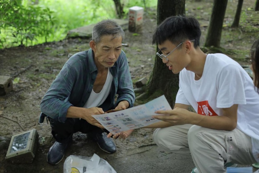 志愿者為村民送相片。共青團成都市委供圖