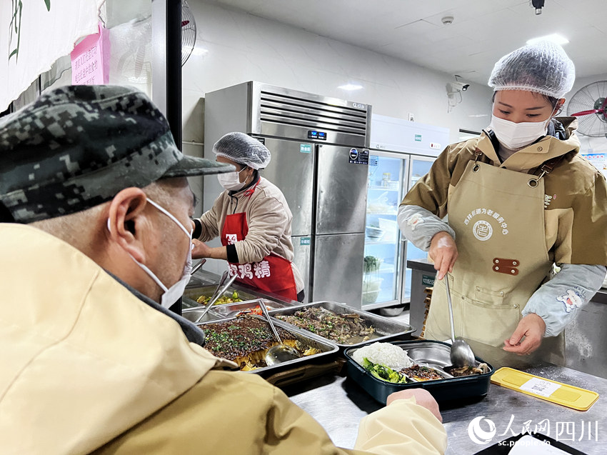 食堂工作人員在為居民打飯。羅尹攝